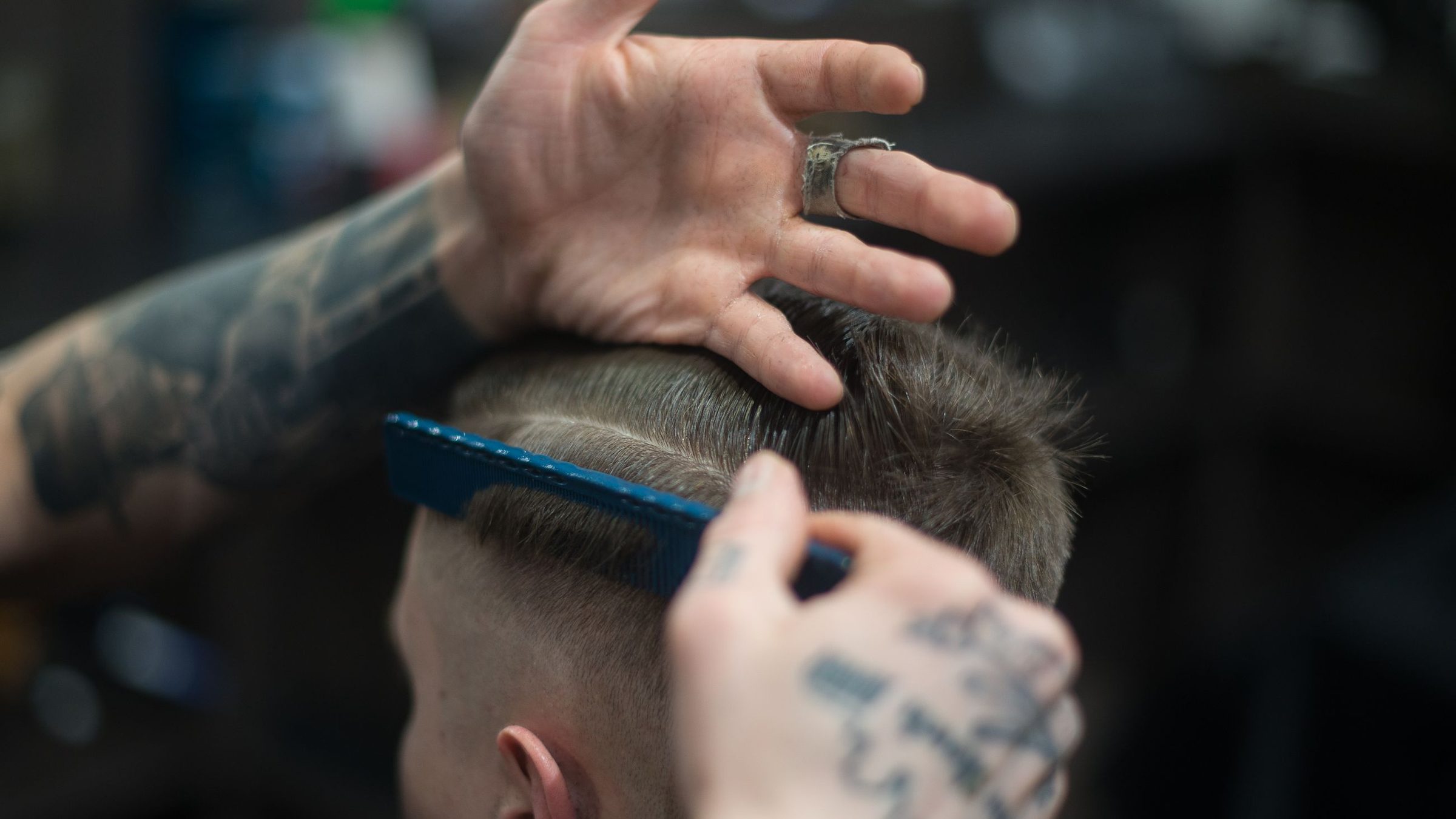 A barber blending a clean fade with clippers and comb